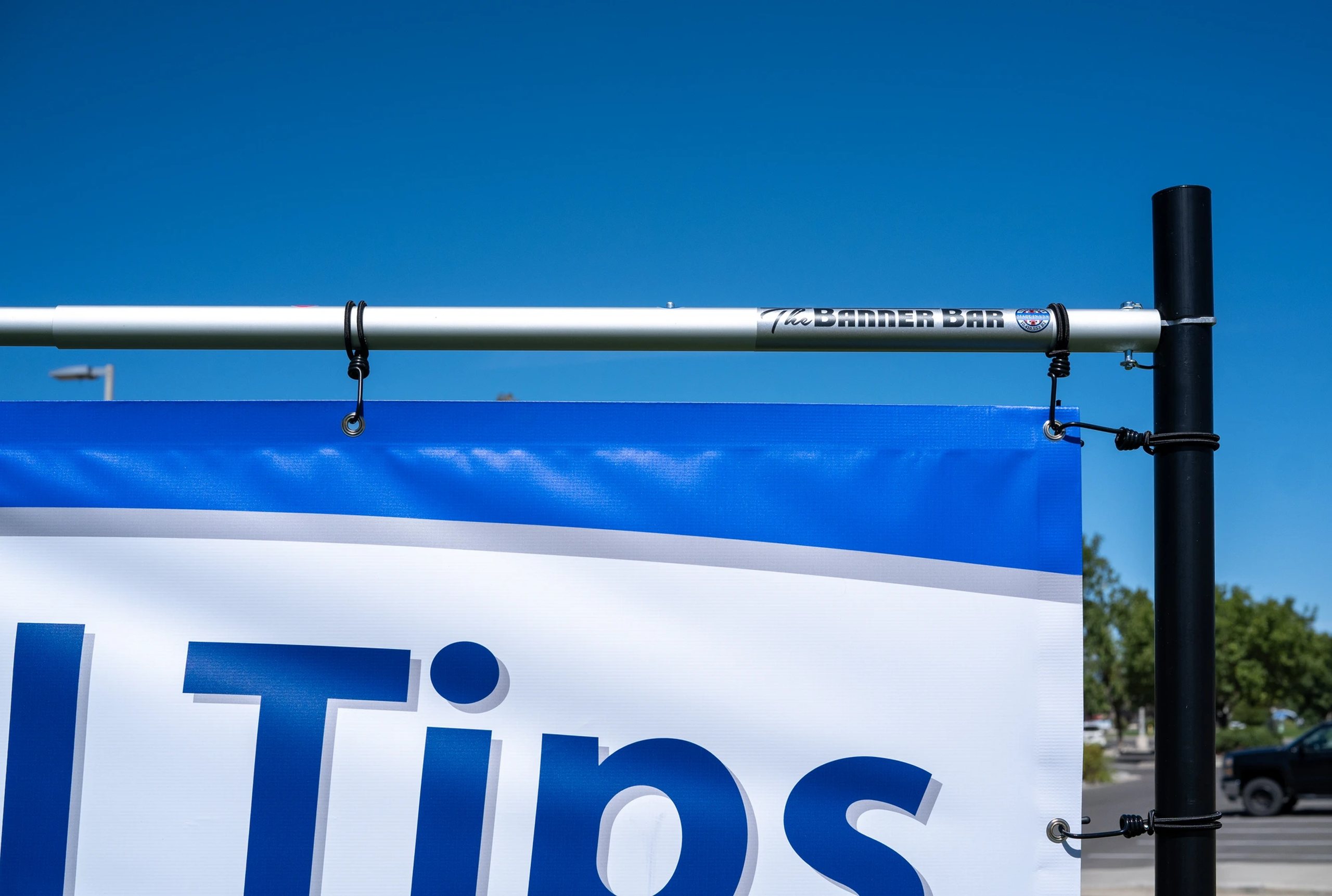 Close-up of The Banner Bar frame holding a blue banner against a clear sky